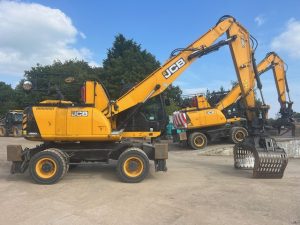 Two yellow JCB excavators parked on a construction site with attachments visible.